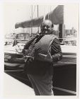 William Conrad wearing a life jacket in front of a sailboat